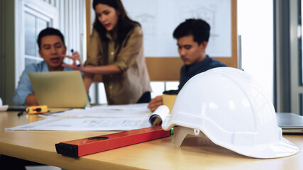 Team of young Asian architects discussing on construction site.