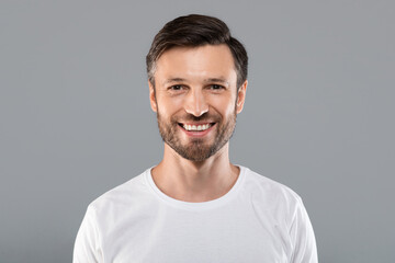Handsome young caucasian man smiling at camera on grey