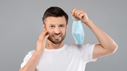 Bearded man scratching his face over grey background
