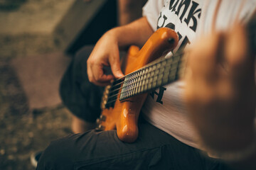 Close up of male hands playing bass guitar.