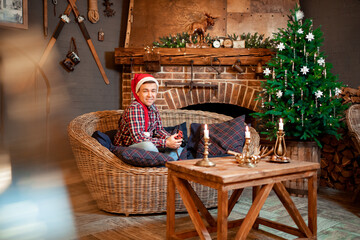 male photographer in a Santa Claus hat in the new year decor of a house with a fireplace. cozy holiday interior of a country house. new year.
