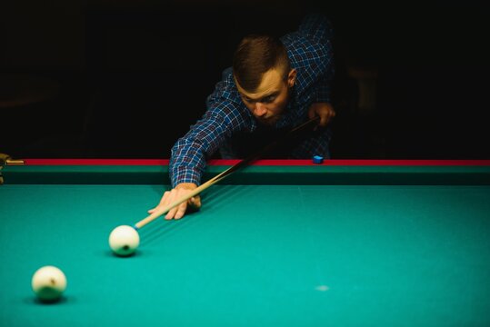 the player takes aim at the ball in Billiards