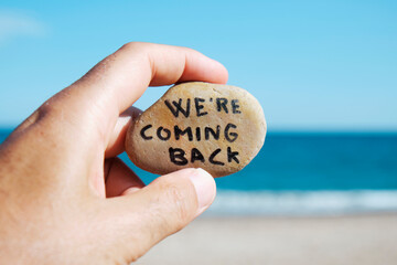 man on the beach and text we are coming back