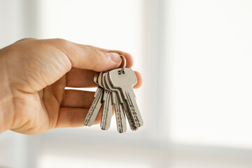 Mens hand holding a set of keys. Realtor is giving the keys to an apartment to clients. Focus on the keys. Bunch of keys in a realtors hand.