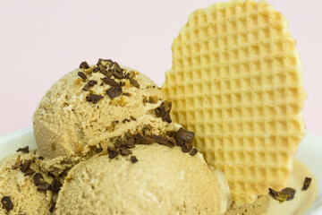 fresh coffee ice cream scoops in a bowl with coffee bean pieces and ice cream wafer