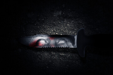 Bloody knife with zombie shadow on the blade with a grunge wall background