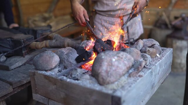 Fire crackling in blacksmith workshop of forging metal. Anonymouse craft smith create objects from wrought iron or steel with helper. Slow motion 4K footage