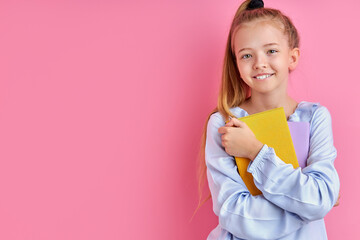 sweet caucasian child girl with books isolated over pink background, adorable girl love studying at school, education concept