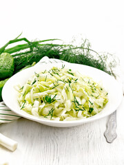 Salad of cabbage with cucumber in plate on white board