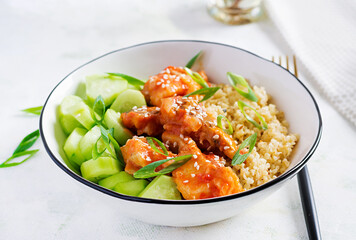 Fish fillet cooked in tomato sauce with bulgur and cucumber on a plate on a light background. Healthy eating concept. Easy cooking.