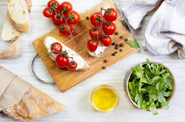 sandwiches with cherry tomatoes salad oil seasoning on a wooden board on a white wooden table top view