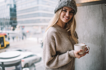 Half length portrait of cheerful female customer with coffee cup enjoying recereation time and...