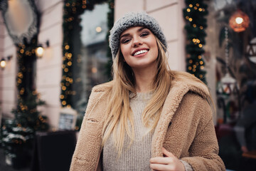 Positive young lady in winter clothes smiling at camera