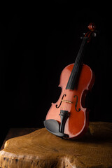 Old and beautiful violin on a rustic wooden surface and black background low key portrait, selective focus.