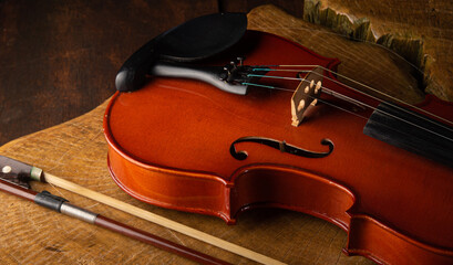 Details of an old and beautiful violin on a rustic wooden surface and black background, low key...