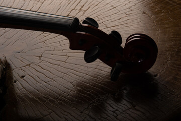 Details of an old and beautiful violin on a rustic wooden surface and black background, low key portrait, selective focus. © Milton Buzon