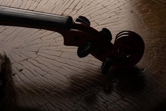 Details of an old and beautiful violin on a rustic wooden surface and black background, low key portrait, selective focus.