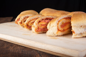 Homemade bread stuffed with ground mortadella and tomato sauce with black background. Low key image, selective focus.