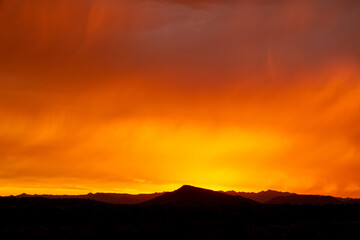 Obraz premium A dramatic cloudy sunset in the desert of Arizona with mountains.