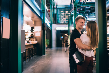 Positive young couple cuddling in modern shopping center