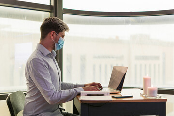 Businessman working in his office, with the sanitary mask to prevent the covid virus.