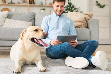 Man at home with digital tablet and labrador
