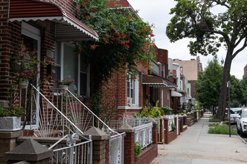 Row of Beautiful Old Brick Homes along an Empty Sidewalk in Astoria Queens New York during Summer