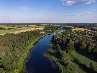 Obraz premium Areal countryside view o river Venta flowing through lovely environment with trees on a warm summer day.