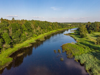 Areal countryside view o river Venta flowing through lovely environment with trees on a warm summer day.
