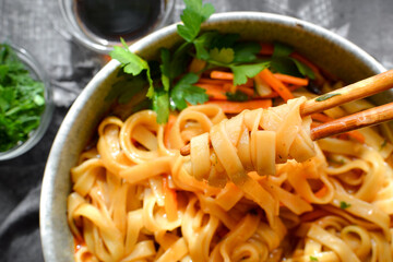 Noodles soup. Top view. Close up. Gray linen napkin. Wooden and concrete dark background. Egg noodles and Chinese sticks.