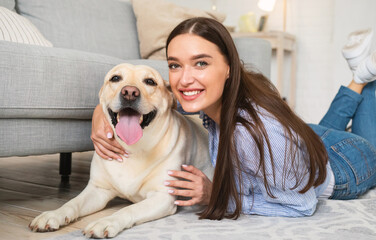 Young happy lady with her labrador lying on floor