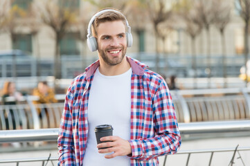 handsome young man wear headphones and smiling while listening music and drinking coffee, morning...