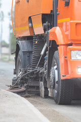 Big orange machine clears the asphalt with a sweeper