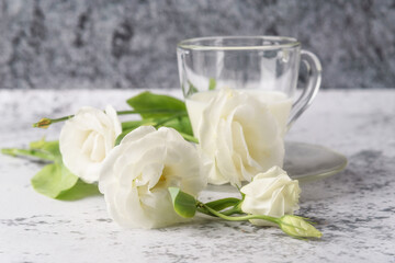 A cup of cold, fresh milk for breakfast. A bouquet of pink, white, purple eustoma for you, on a gray concrete table.
