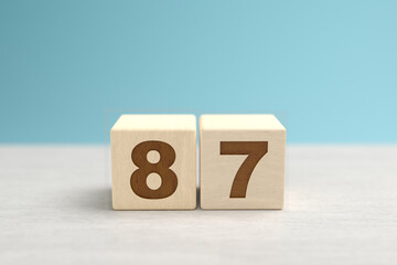 Wooden toy blocks forming the number 87.