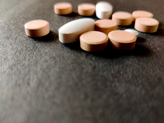 Concept of tablets.Covid-19 corona virus cure.White and orange color medical pills on black background.