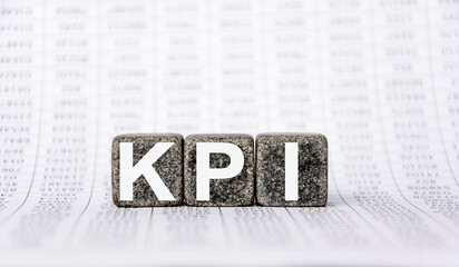 three stone cubes on the background of white financial statements, tables with the word KPI Key performance indicator. Strong business concept