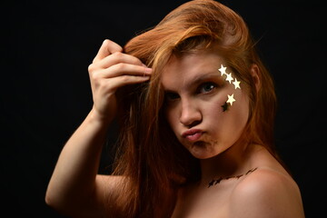 Beautiful young woman face close up portrait in studio on black. various emotions. foil stars glued to the face