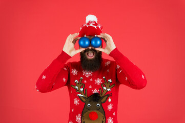 Watching you. Festive decorations. Essential winter activities for families. Hipster bearded man wear winter sweater hat hold balls red background. New year concept. Christmas party. Winter outfit