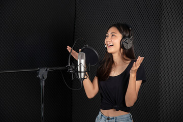 Young lady singing  in music studio recording room