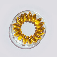 Omega3 gel capsule. Yellow vitamin. Health eating. Dietology drug. Fish oil supplement. Microdosing concept. Golden color softgel collagen. Grey background. Medicine immunity cosmetics