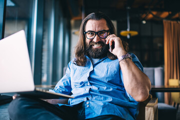 Portrait of man bearded mature man talking on mobile phone furious about troubles on remote job, angry caucasian 40years businessman with laptop computer stressed during smartphone conversation