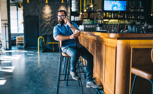 Man talking on phone while sitting at bar rack - Powered by Adobe