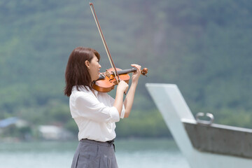 Beautiful asian woman hold violin on ship and nature background, in emotion feeling happy and...