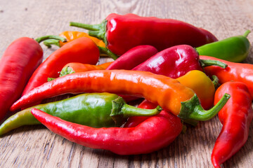 Hot chili pepper red, green, yellow scattered on an old wooden table