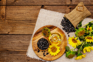 Sunflower oil in glass cruet with flower head and seeds in wooden bowl