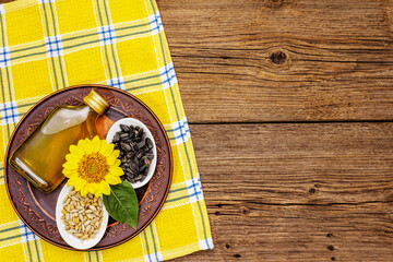 Sunflower oil in glass cruet with flower head and seeds in wooden bowl