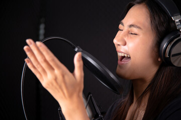 Young lady singing  in music studio recording room