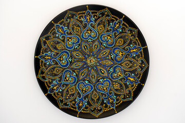 Decorative ceramic plate with black, blue and golden colors, painted plate on white background , dot painting