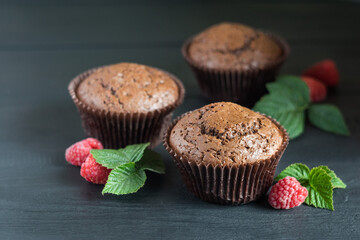 Chocolate muffins with raspberries on dark wooden background, selective focus
